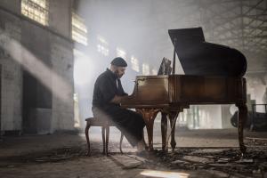 Australia-based Spanish composer and pianist Jordi Forniés playing a grand piano in a cinematic industrial space.
