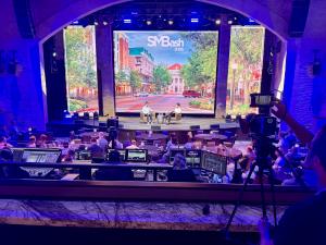 Elite Video videographer filming corporate event with 4K camera and wireless audio equipment