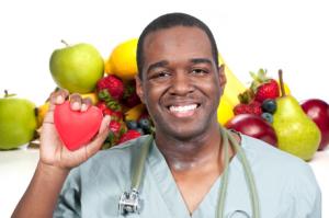 photo of a health care professional in a scrub uniform with a stethescope with lots of fresh fruits around him