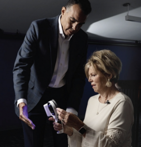 Two dental professionals examining the illuminated VELscope Mantis handpiece during a demonstration