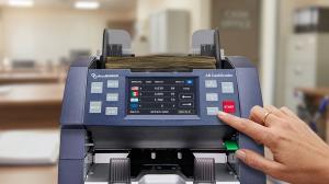 AccuBANKER, a Miami-based leader in commercial cash-handling infrastructure since 1981, today announced the launch of the AB8000 CashGrader, its most advanced bill counter and authentication system to date AccuBANKER AB8000 CashGrader bill counter being operated in a professional banking environment showing multi-currency touchscreen display and dual sorting pockets
