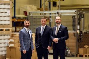 TOSLA management team portrait featuring Uroš Gotar (CIO), Uroš Benedičič (COO), and Primož Artač (CEO & Founder) standing together in the Super Factory TOSLA 3