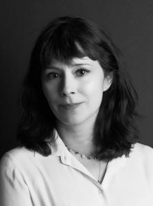 Black-and-white portrait of Traci L. Slatton, director of HEROIC, wearing a light blouse and necklace against a dark studio background. She faces the camera with a calm expression for the documentary on Sabin Howard and the National WWI Memorial.