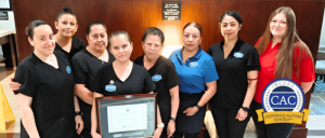 Hampton Inn Visalia staff in uniforms posing indoors, one holding a framed certificate.