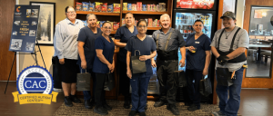 Comfort Suites Visalia staff in work uniforms posing inside a break room with snacks and beverages in the background.