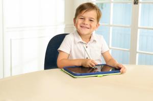 A pre-K child uses a tablet and stylus from Smile Zemi at the dining room table.