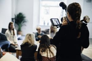 Videographer filming a media interview in a studio.
