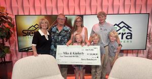 Joel Janson and his two young sons stand with Mike, Kimberly and their daughter, who holds a large $10,000 Sierra Homebuyers check, on the KTVN “2 Plus You Nevada” set.