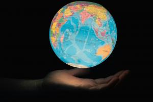 Illuminated world globe held in an open hand.