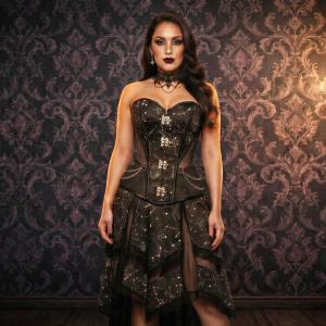 Model wearing a black celestial constellation print overbust corset with sweetheart neckline, mesh side panels, decorative clasps, and matching layered gothic skirt against a dark Victorian backdrop.