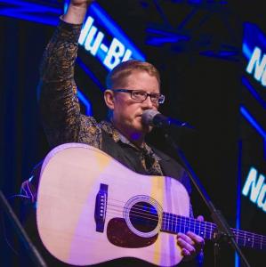 Daniel Routh of the band, Nu-Blu, onstage with guitar. The musician manages a busy life with Alpha-Gal Syndrome