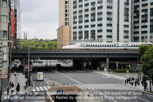A view from the former elevated expressway KK Line on the outskirts of Ginza.  A superfast Shinkansen train flashes by with Hibiya Park in the background.