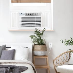 As temperatures continue to rise across much of the United States, Keystone has announced a series of limited-time summer deals on air conditioners, dehumidifiers, and home comfort products designed to help consumers stay comfortable during the season's hottest months White Keystone window AC unit installed in a bedroom window above a bed, ideal for cooling apartments and residential spaces.