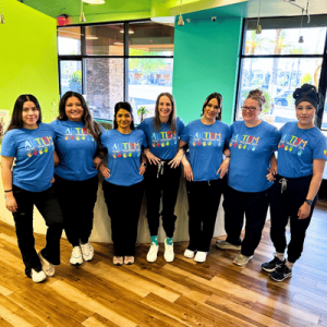 Group of seven women standing indoors, wearing matching blue 
