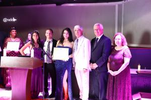 Tamara Mechael poses on stage with her Ambassador for Peace certificate beside Universal Peace Federation representatives and event organizers at the Peace Gala.