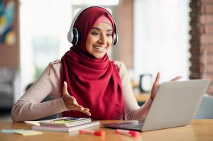 Happy young muslim woman in headscarf having video conference