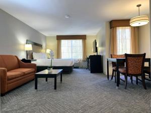 Renovated king guest room at the Best Western Escondido Hotel featuring a king bed, loveseat, coffee table, dining set, and updated finishes.