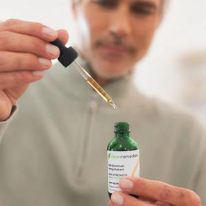 man holding a dropper of CBD oil from Clean Remedies