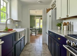 Luxury staged galley kitchen with navy lower cabinets, white upper cabinets, farmhouse sink, brass hardware, marble-look countertops, and professional home staging in Richmond, Virginia.