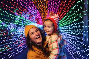 joyful mom and daughter inside the rainbow light tunnel at the cambria christmas market