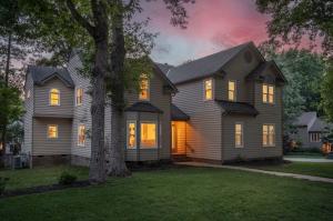 Twilight exterior of a professionally staged luxury home in Richmond, Virginia featuring mature trees, illuminated windows, and exceptional curb appeal.