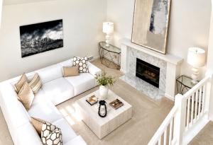 Professionally staged great room with vaulted ceilings, white sectional sofa, modern fireplace, oversized artwork, and contemporary furnishings