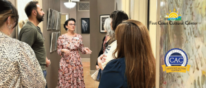 First Coast Cultural Center renews its Certified Autism Center™ (CAC) designation through the International Board of Credentialing and Continuing Education Standards (IBCCES) A woman in a floral dress explains art to a group inside a gallery at First Coast Cultural Center, certified autism center.