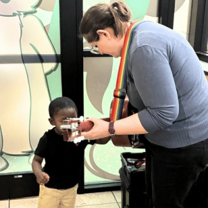 A staff member shows a child a sensory-friendly toy during an interactive activity in an indoor setting.