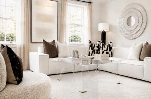 Luxury staged living room in Richmond, VA by Jsquared Interior Staging and Design with white sectional, acrylic coffee table, layered neutral textures, and sculptural mirror