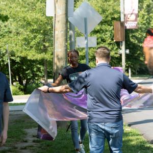 Artist Nile Livingston helps carry and install a mural panel for the