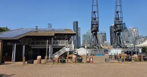 Exterior of Docklands Sailing and Watersports Centre with dockside cranes and the Canary Wharf skyline behind