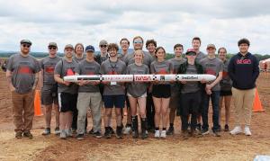 Rose Rocketry team members holding their rocket.