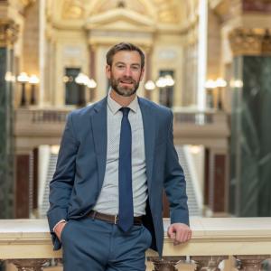 Nowlan Injury Law is proud to announce that Attorney Evan Tenebruso has been certified for inclusion in the State Bar of Wisconsin's Pro Bono Honor Society, recognizing his commitment to providing free legal services to individuals and families in need A photo of Attorney Evan Tenebruso standing inside the Madison Capitol
