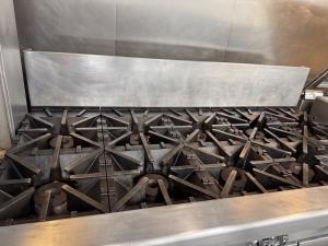 Commercial restaurant range after professional deep cleaning of burners, cooking surfaces, and surrounding stainless-steel areas