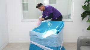 Two Chicks Moving crew member wrapping furniture with protective blankets before a move