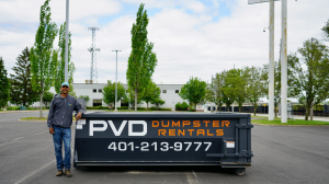 PVD Dumpster Rentals, a family-owned roll-off dumpster company based in Cranston, is expanding its same-day and next-day service to meet rising demand from homeowners and contractors across Rhode Island and southern Massachusetts Jamaal Hazard, owner of PVD Dumpster Rentals, standing beside a branded roll-off dumpster in Cranston RI