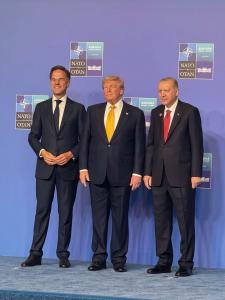 NATO Secretary General Mark Rutte, US President Donald Trump and Turkish President Recep Tayyip Erdoğan stand side by side in dark suits in front of a blue NATO Ankara Summit backdrop.