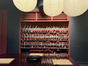 Japanese kitchen knives displayed on red shelving inside the MUSASHI JAPAN Kyoto Kawaramachi store.