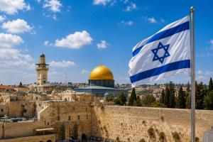 Panoramic view of Jerusalem with the Israeli flag waving above the Old City, representing real estate investment in Israel.