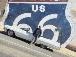John Paget, standing in front of a classic car with a Route 66 mural in the background