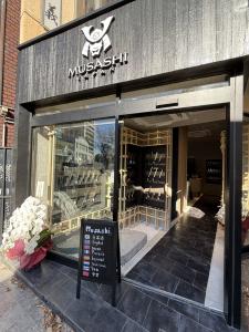 Exterior view of MUSASHI JAPAN Omotesando Station Front Store in Tokyo with multilingual signage and knife displays