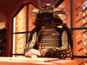 Samurai armor display inside MUSASHI JAPAN Kanazawa Higashi Chaya Store with Japanese kitchen knives displayed in the background