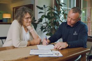 A Home Buying Specialist from Jeff Buys Your House reviews paperwork with a homeowner during a consultation about selling an inherited property in Chicagoland.