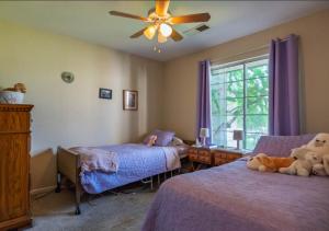A cozy resident bedroom with twin beds, purple quilts, and stuffed animals in a residential care facility.