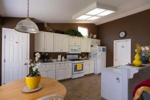 A view of the kitchen and dining area with white cabinetry, white appliances, and a yellow flowerpot on a wooden table.