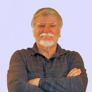 Portrait of author Keith Engelhardt with folded arms, smiling and wearing a dark gray long-sleeve polo shirt against a light lavender background.
