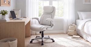 A white executive leather office chair with a high padded backrest and quilted stitching, placed at a light wood study desk in a bright student bedroom.