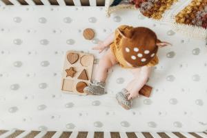 Baby Playing in a Crib with a Comfy Joey + Joan Sheet