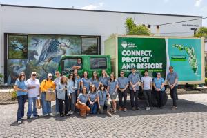 Photo of Florida Wildlife Corridor Foundation staff in front of wildlife mural and company expedition vehicle