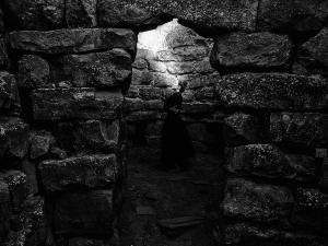 Elizabeth Yochim standing inside the Bronze Age stone chamber of Nuraghe Piscu in Sardinia, Italy, looking upward toward an opening in the ancient structure during the creation of Between Earth and Sky.